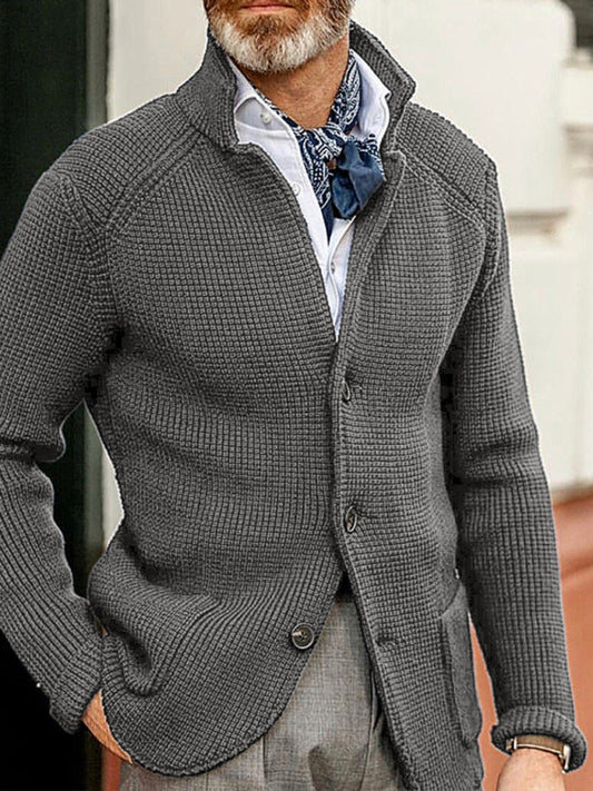 Man wearing a gray textured jacket cardigan with a patterned scarf and white shirt.